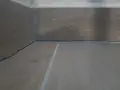 Angolo di una stanza con pavimento in legno e battiscopa. Si vedono le crepe tra il battiscopa e il muro, un dettaglio da considerare dopo il massetto.