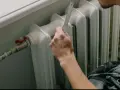 Mano con righello vicino a termosifone, pronto a cambiare valvola termostatica senza svuotare impianto.