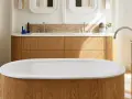 Una vasca da bagno di lusso con finiture in legno e marmo, rubinetteria cromata e un mobile doppio lavabo in legno.
