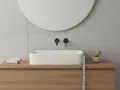 Misurazione dell'altezza lavabo da terra in un bagno moderno con mobile in legno e specchio rotondo.