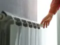 Mano che regola la valvola di un termosifone. Scopri quanto costa cambiare i termosifoni per un riscaldamento efficiente.