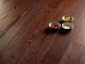 Superficie in parquet massello o prefinito con venature marcate. Tre ciotoline con elementi decorativi colorati.