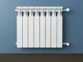 Un termosifone bianco su muro blu. Si intravedono i tubi interni e la valvola termostatica, mostrando come è fatto un termosifone all'interno.