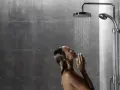 Donna sotto una doccia walk in dimensioni ideali, con le mani giunte sotto il getto d'acqua.