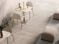 Un'area lounge moderna con tavolini, sedie e pouf su eleganti mattonelle senza fuga effetto pietra.