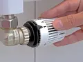 Mano che regola la manopola del termostato per misurare la temperatura dei termosifoni.