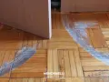 Rimozione di parquet incollato con segni di usura sul pavimento in legno.