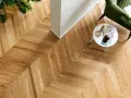 Un elegante parquet oliato a spina di pesce, con un tavolino bianco e una poltrona verde. Scopri come pulire il tuo parquet oliato per mantenerlo splendente.