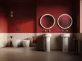 Bagno moderno con wc, bidet e due lavabi a colonna. L'artceramica bianca risalta sulle pareti rosse e le piastrelle chiare.