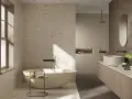 Bagno moderno con vasca freestanding e lavabo su mobile in legno. Il pavimento fap, con le sue venature chiare e inclusioni dorate, riflette la luce naturale.