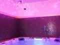 Jacuzzi con luci soffuse e mosaici viola, un'oasi di relax per la cromoterapia spa.