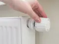 Mano che regola la manopola di un termosifone per ottimizzare la potenza.