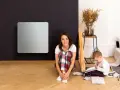 Donna e bambino in un soggiorno con pannelli radianti infrarossi. Nessuna controindicazione visibile.