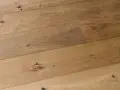 Dettaglio di assi di parquet prefinito in legno chiaro con nodi evidenti. Lo spessore del legno conferisce robustezza.