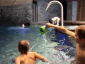 Bambini giocano in piscina, con un annaffiatoio. Nessuna indicazione su sauna età minima.