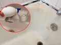 Un bicchiere viene riempito con un liquido da una bottiglia bianca, un passo per imparare come pulire la vasca da bagno macchiata.
