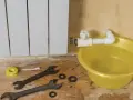 Riparazione di un termosifone che perde acqua e presenta ruggine. Attrezzi e bacinella gialla pronti per l'intervento.