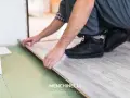 Installazione di un parquet flottante con finitura effetto legno chiaro. Un artigiano posa le tavole con cura.