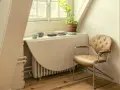 Angolo studio con sedia in pelle e un tavolo ribaltabile che nasconde un termosifone. Ricorda: non coprire i termosifoni per un riscaldamento efficiente.