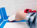 Applicazione sigillante per una doccia senza piatto, impermeabilizzazione perfetta con nastro blu.