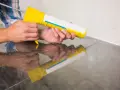 Applicazione di silicone con pistola per sigillare il box doccia.