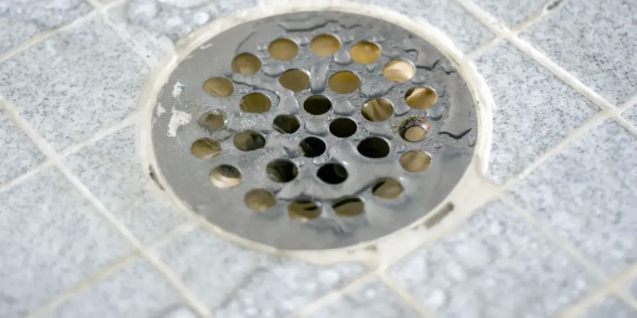 Scarico doccia a pavimento con piastrelle grigie e acqua. La pendenza doccia a pavimento assicura il corretto deflusso.