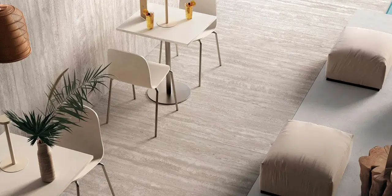 Un'area lounge moderna con tavolini, sedie e pouf su eleganti mattonelle senza fuga effetto pietra.
