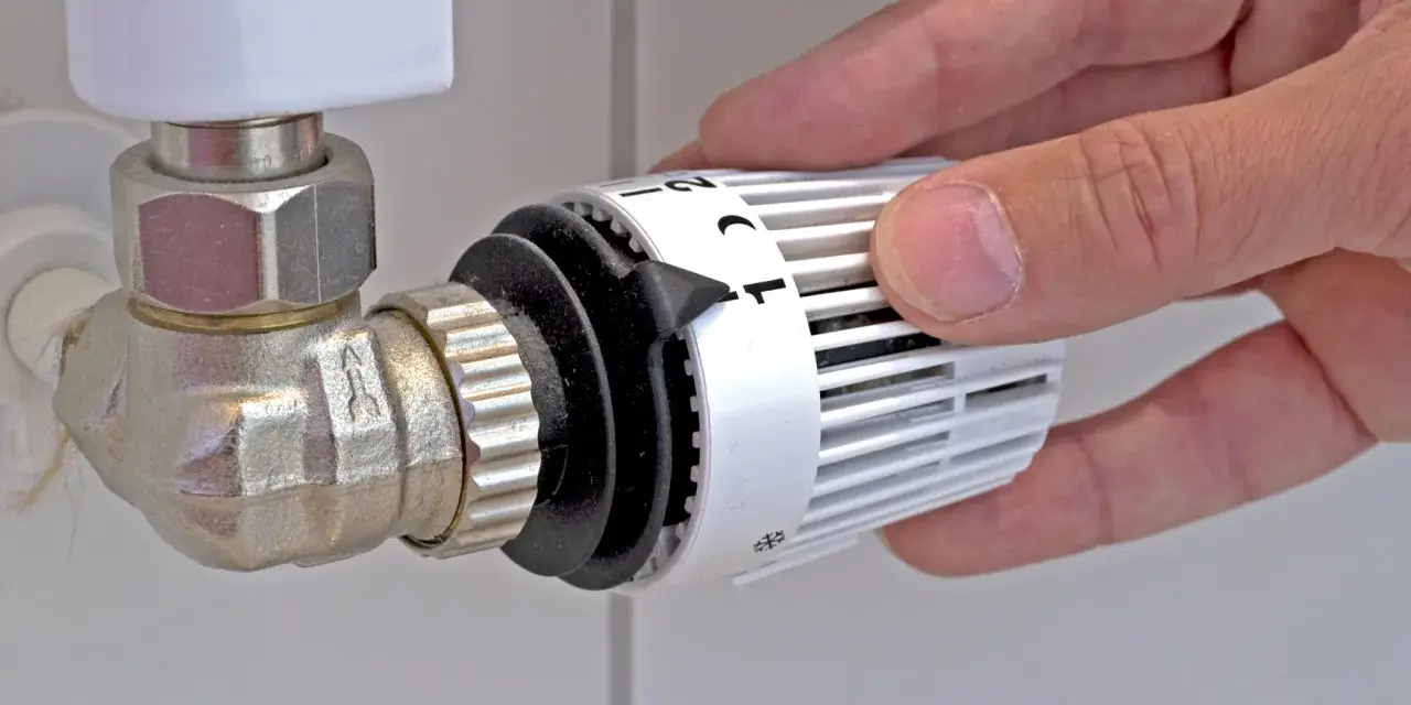 Mano che regola la manopola del termostato per misurare la temperatura dei termosifoni.