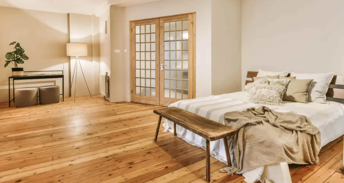 Camera mostra un letto, un armadio e un pavimento in legno. Il parquet è stato pulito con alcool, rendendolo brillante.