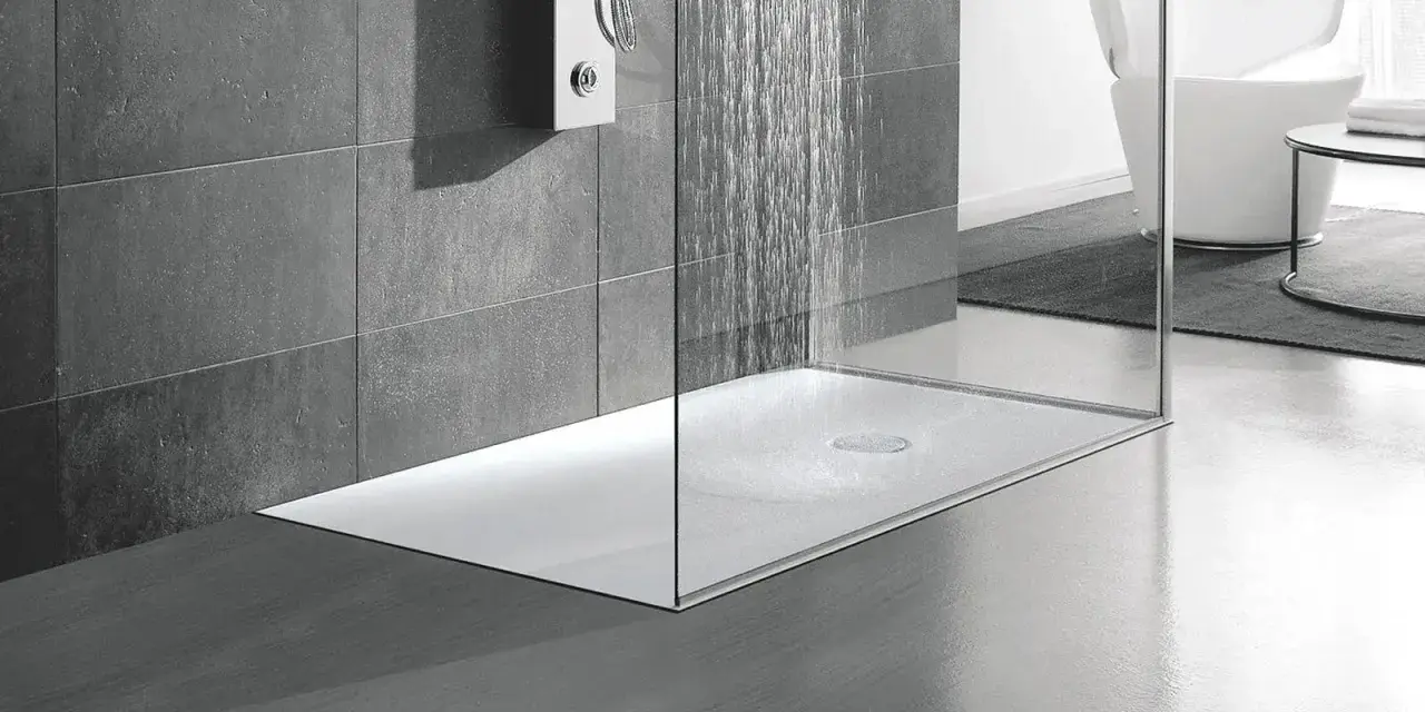 Una doccia moderna a pavimento con pareti in vetro e piastrelle grigie. L'acqua scorre dal soffione, creando un'atmosfera rilassante.