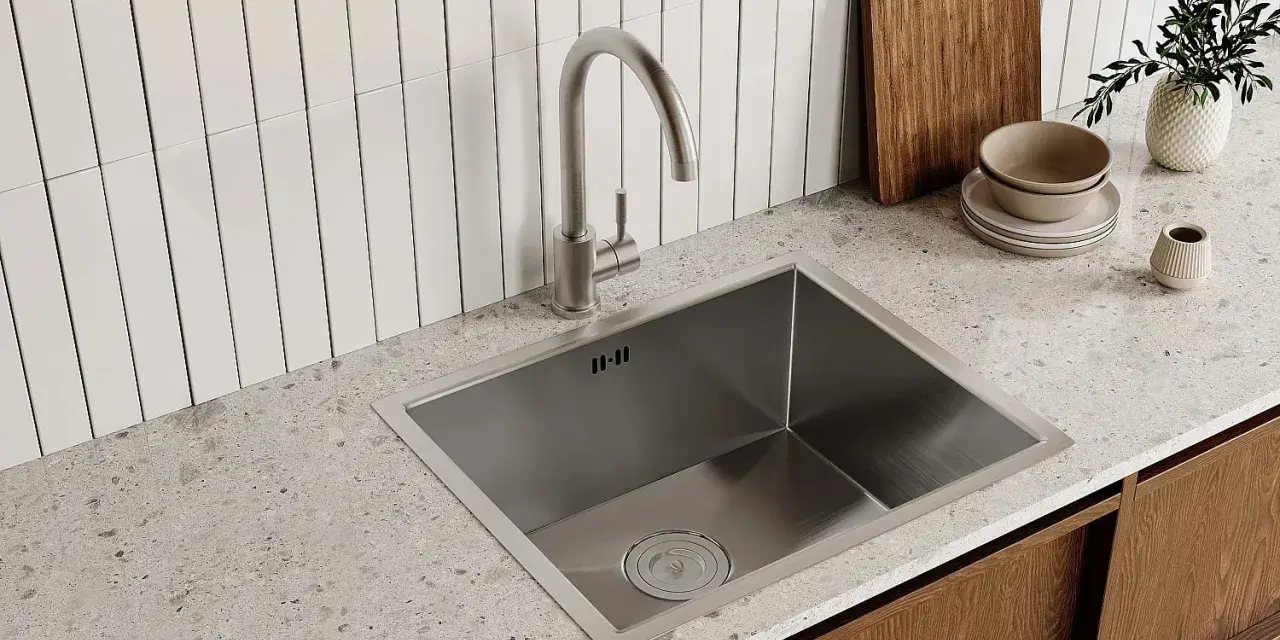 Rubinetto cucina moderno in acciaio inox, pronto per essere smontato. Sotto, un lavello squadrato e un piano in quarzo.