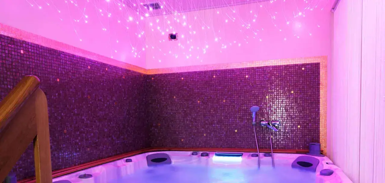 Jacuzzi con luci soffuse e mosaici viola, un'oasi di relax per la cromoterapia spa.
