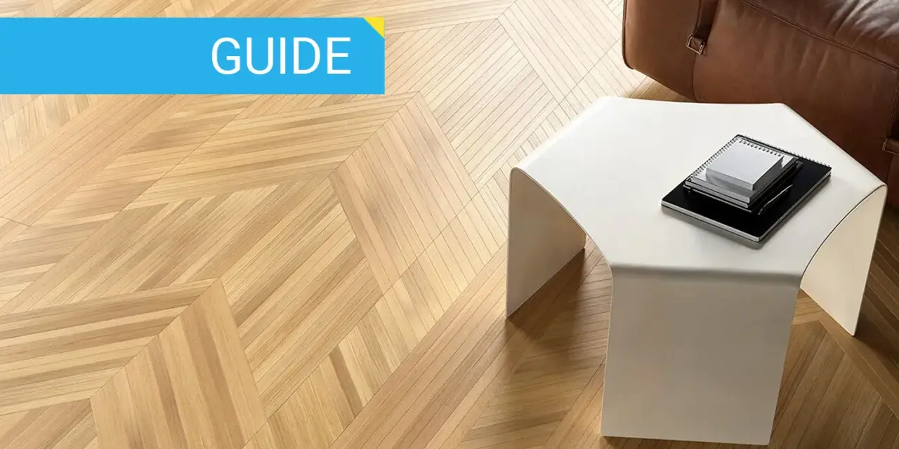 Guida: parquet spazzolato pro e contro. Pavimento in legno con motivo a spina di pesce, tavolino bianco e divano in pelle marrone.