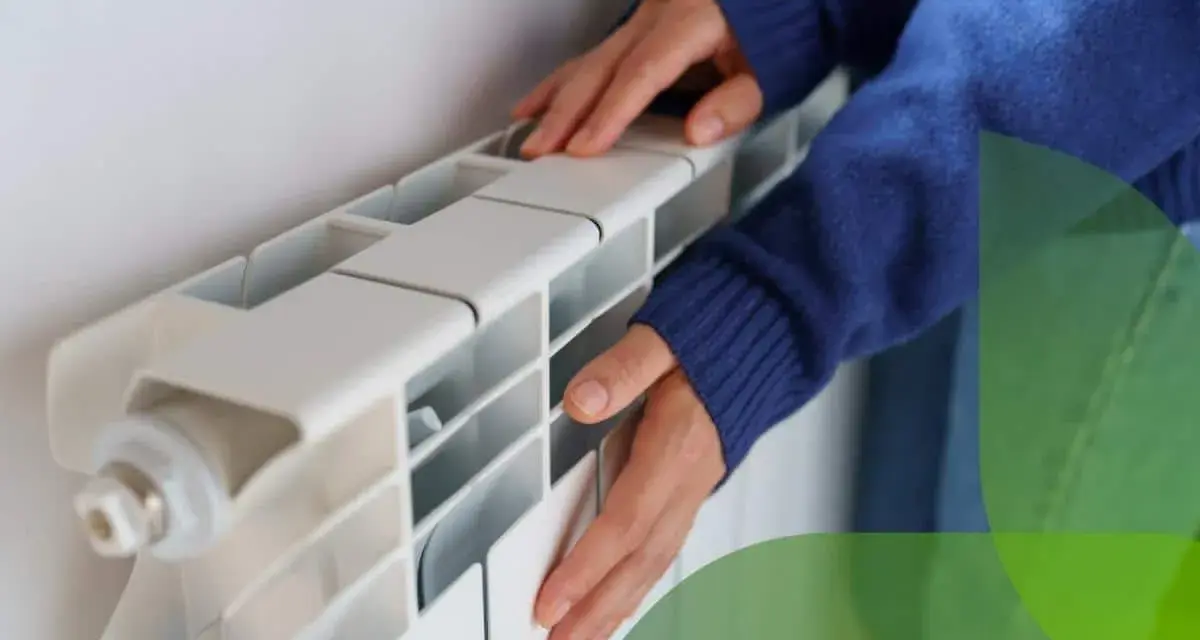 Mani che toccano un termosifone bianco, suggerendo come svuotare termosifone per la manutenzione.