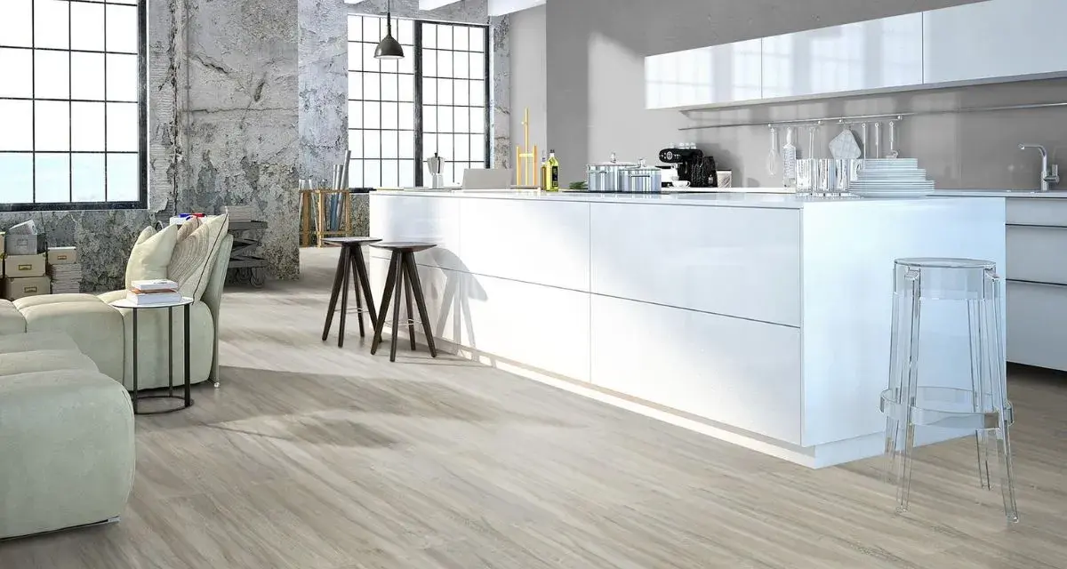 Cucina moderna con isola bianca, divano e pavimenti in legno chiaro. Quanti pavimenti si possono sovrapporre per creare questo look?
