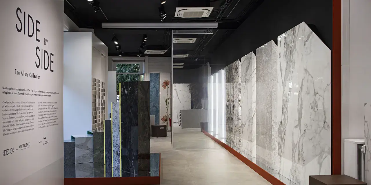 Interno showroom con lastre di marmo e design, esposizione "Side by Side" di Cotto d'Este, rivenditori di eccellenza.