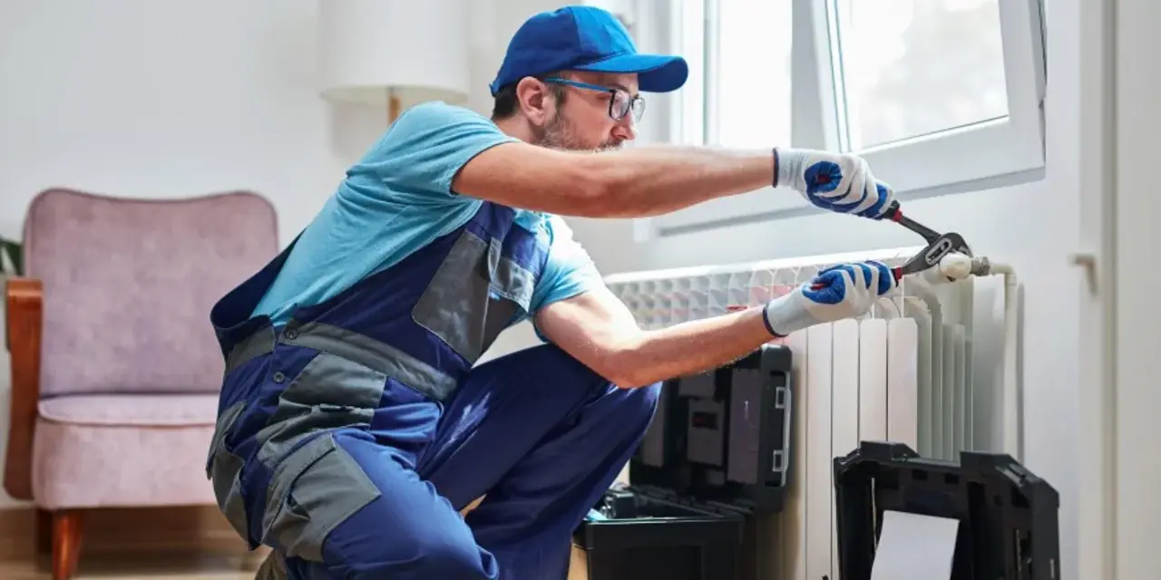 Tecnico con attrezzi lavora su termosifone. Scopri il lavaggio termosifoni in ghisa costo per un riscaldamento efficiente.