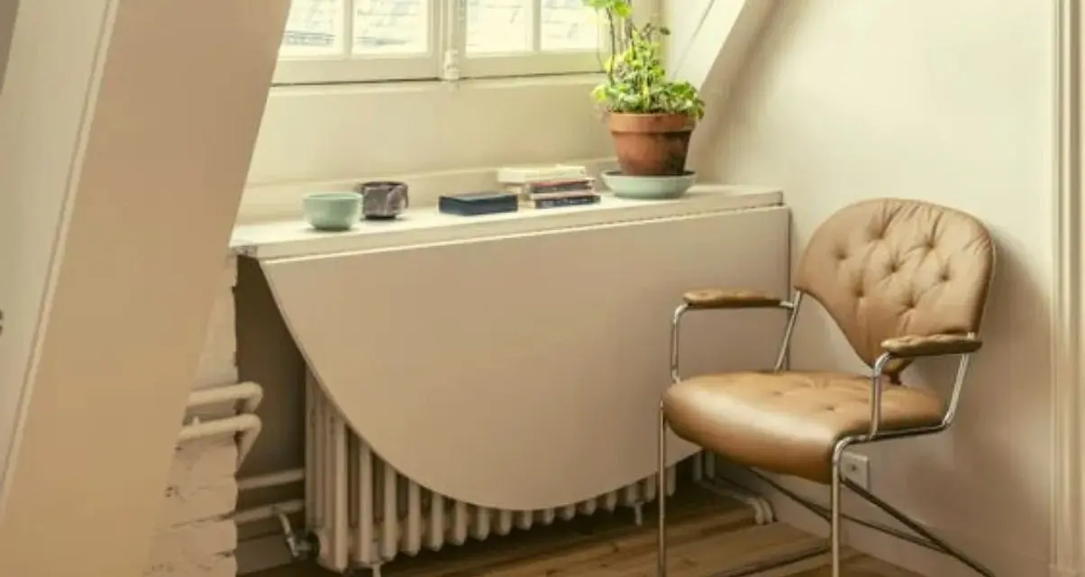 Angolo studio con sedia in pelle e un tavolo ribaltabile che nasconde un termosifone. Ricorda: non coprire i termosifoni per un riscaldamento efficiente.