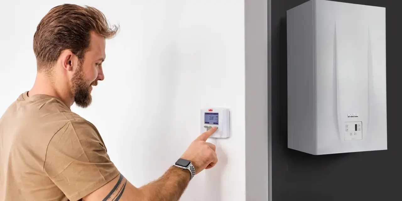 Uomo interagisce con termostato digitale, mostrando la differenza tra termostato e cronotermostato per ottimizzare il riscaldamento.
