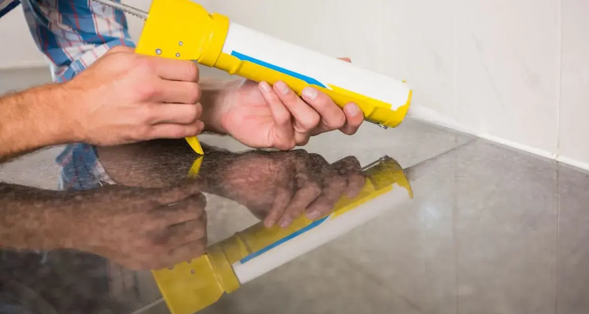 Applicazione di silicone con pistola per sigillare il box doccia.