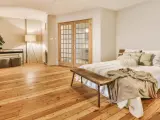 Camera mostra un letto, un armadio e un pavimento in legno. Il parquet è stato pulito con alcool, rendendolo brillante.