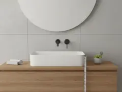 Misurazione dell'altezza lavabo da terra in un bagno moderno con mobile in legno e specchio rotondo.