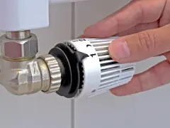 Mano che regola la manopola del termostato per misurare la temperatura dei termosifoni.