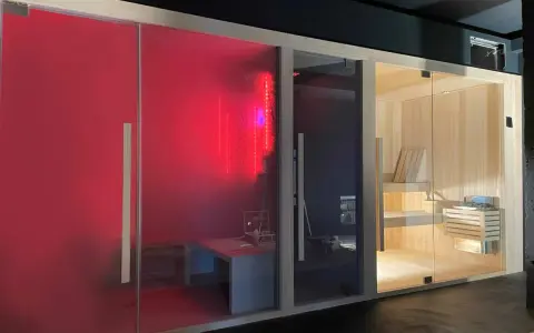 Tre cabine per un'esperienza spa in casa: una rossa con luci LED, una scura e una in legno con sauna tradizionale.