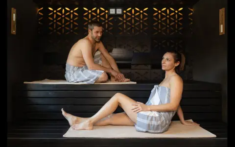 Coppia rilassata in un bagno turco, con clessidra per misurare il bagno turco quanto tempo.