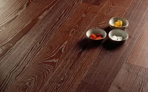 Superficie in parquet massello o prefinito con venature marcate. Tre ciotoline con elementi decorativi colorati.