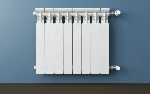 Un termosifone bianco su muro blu. Si intravedono i tubi interni e la valvola termostatica, mostrando come è fatto un termosifone all'interno.