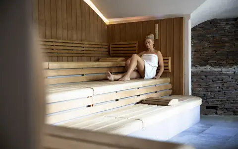 Donna rilassata in sauna, un'esperienza che distingue la differenza tra spa e terme per il benessere.