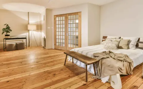 Camera mostra un letto, un armadio e un pavimento in legno. Il parquet è stato pulito con alcool, rendendolo brillante.