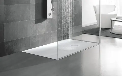 Una doccia moderna a pavimento con pareti in vetro e piastrelle grigie. L'acqua scorre dal soffione, creando un'atmosfera rilassante.